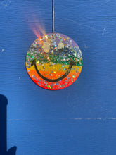 Rainbow glitter hanging smiley with gold eyes and mouth.