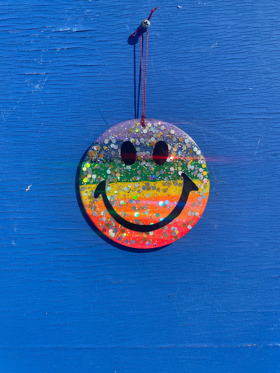 Rainbow glitter hanging smileys face.