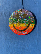 Rainbow glitter hanging smiley with gold eyes and mouth.