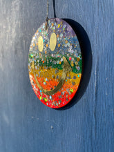 Rainbow glitter hanging smiley with gold eyes and mouth.