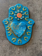 Large Hamsa hand in blue decorated with a resin heart, horseshoes and an evil eye